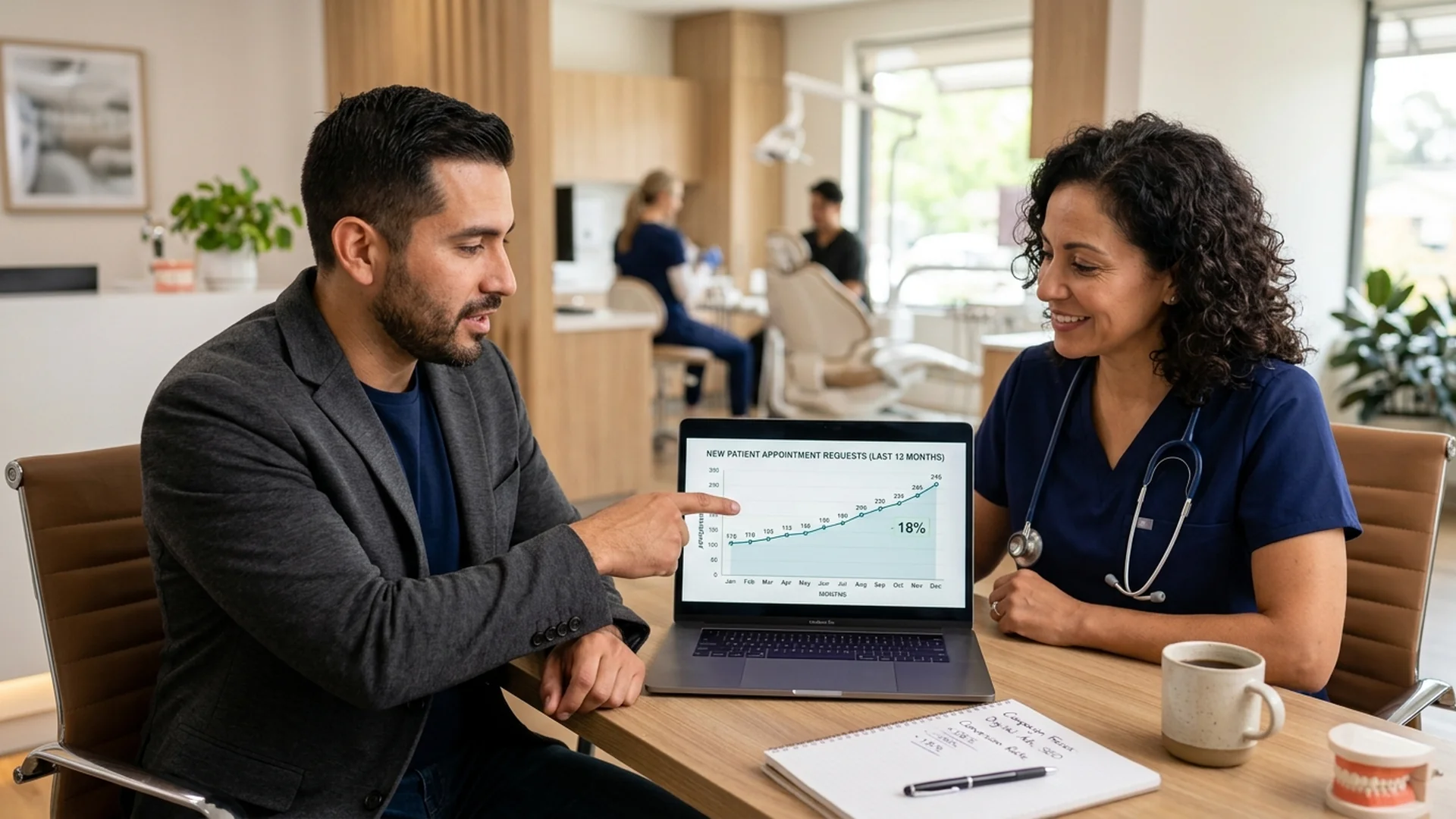 A marketing strategist sitting at a desk with a dental practice owner, pointing to co — Dentist